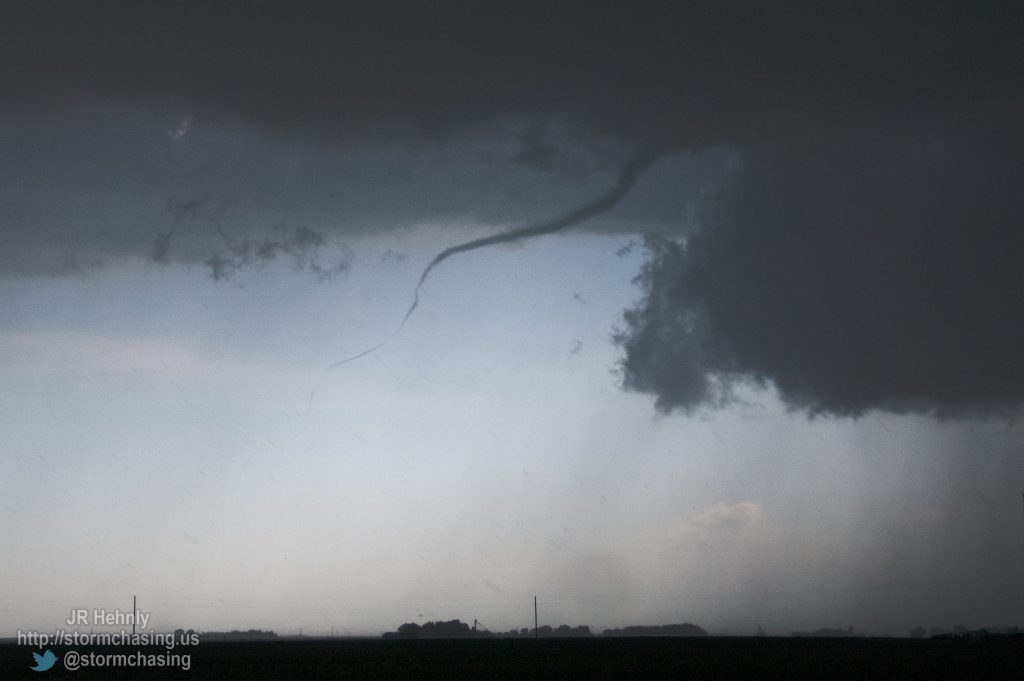 First tornado of the day becomes visible to our southwest as we blast east to escape the hail core. Only a very thin rope is seen, and the debris cloud on the ground is far removed from the base of the supercell. - 6/20/2011 5:26:09 PM - 4 miles southeast of Hampton, NE - Hampton, NE - 